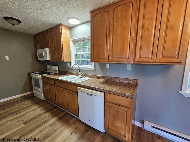 kitchen featuring white appliances, dark wood-type flooring, sink, a baseboard heating unit, and a textured ceiling