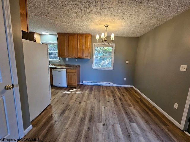 kitchen with white appliances, hanging light fixtures, baseboard heating, and a healthy amount of sunlight