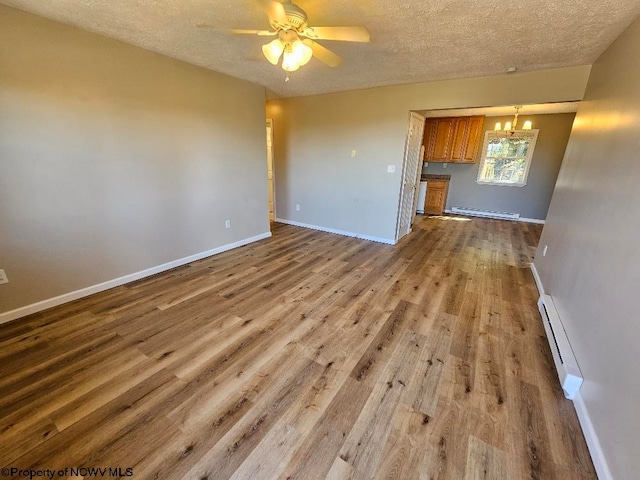 unfurnished living room with wood-type flooring, ceiling fan with notable chandelier, a baseboard heating unit, and a textured ceiling