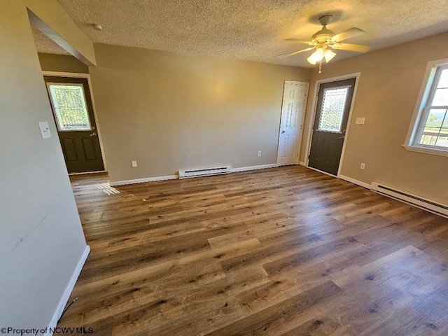 unfurnished room with a textured ceiling, hardwood / wood-style flooring, and baseboard heating