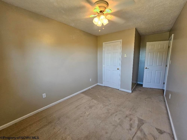 unfurnished bedroom featuring light colored carpet, ceiling fan, a closet, and a textured ceiling