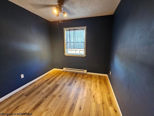 spare room featuring wood-type flooring, a textured ceiling, a baseboard heating unit, and ceiling fan