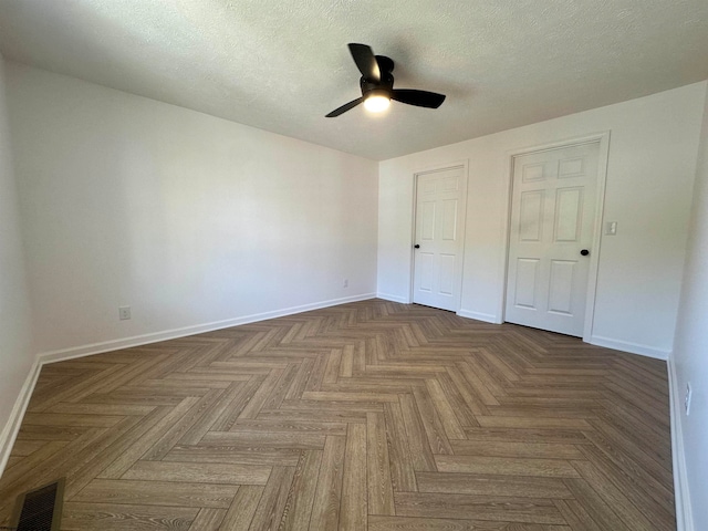 unfurnished bedroom featuring a textured ceiling, dark parquet floors, and ceiling fan