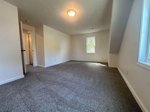 empty room featuring a textured ceiling and dark carpet