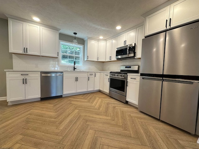 kitchen featuring white cabinetry, tasteful backsplash, stainless steel appliances, and hanging light fixtures