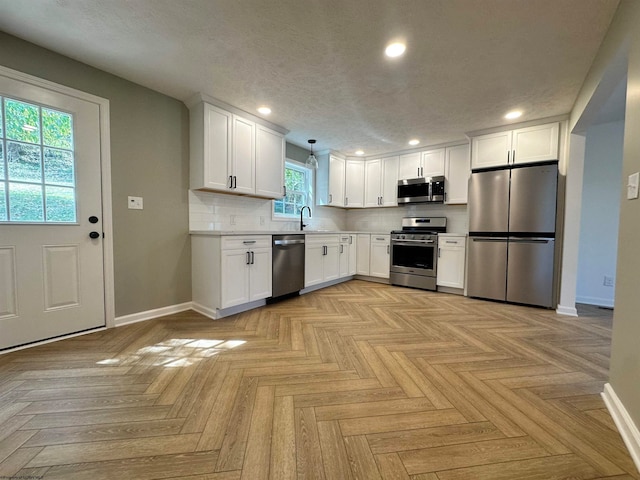 kitchen with sink, decorative light fixtures, stainless steel appliances, and white cabinets