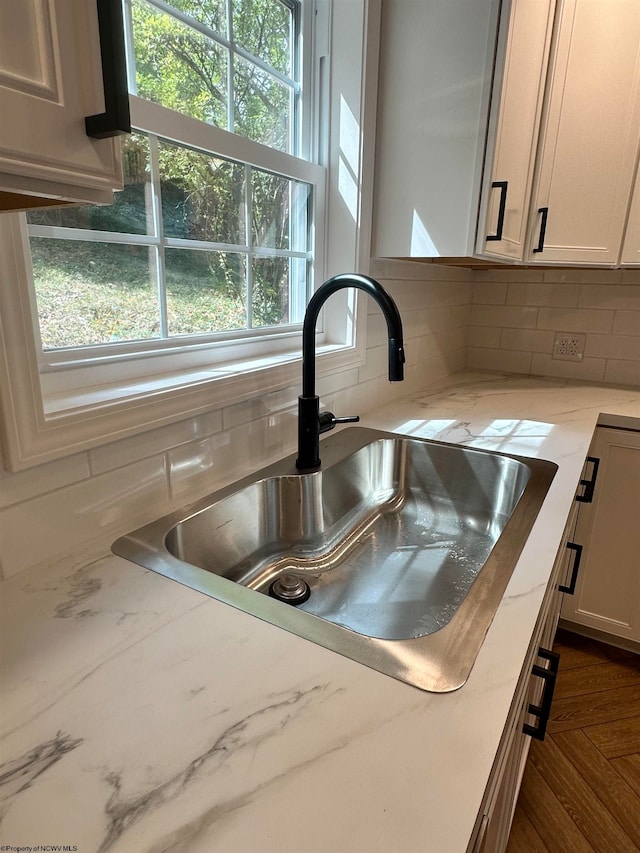 kitchen with plenty of natural light, sink, light stone countertops, and backsplash