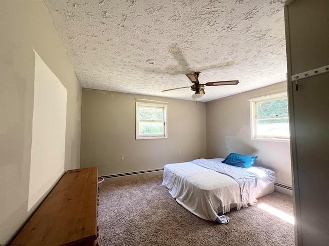 bedroom with a baseboard heating unit, ceiling fan, carpet floors, and a textured ceiling