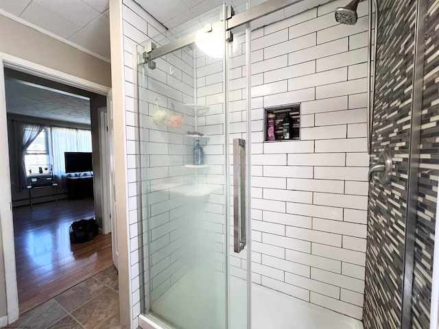 bathroom with a shower with shower door, a baseboard radiator, ornamental molding, and wood-type flooring