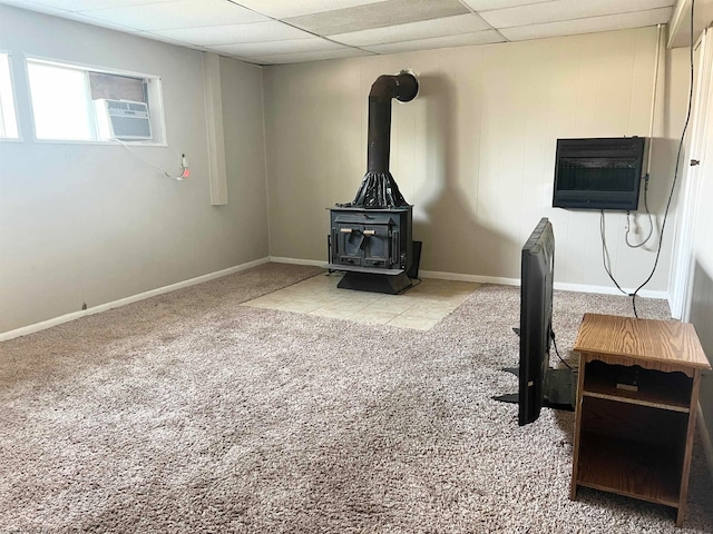 home office with cooling unit, a paneled ceiling, a wood stove, and light carpet