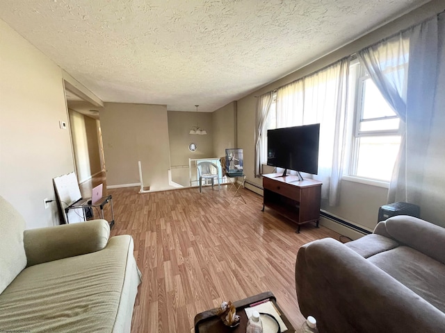 living room with light wood-type flooring, a baseboard heating unit, and a textured ceiling