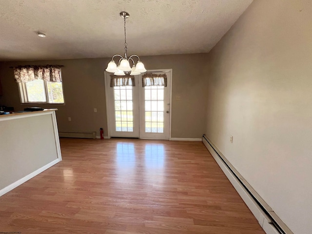 empty room with plenty of natural light, baseboard heating, and wood-type flooring