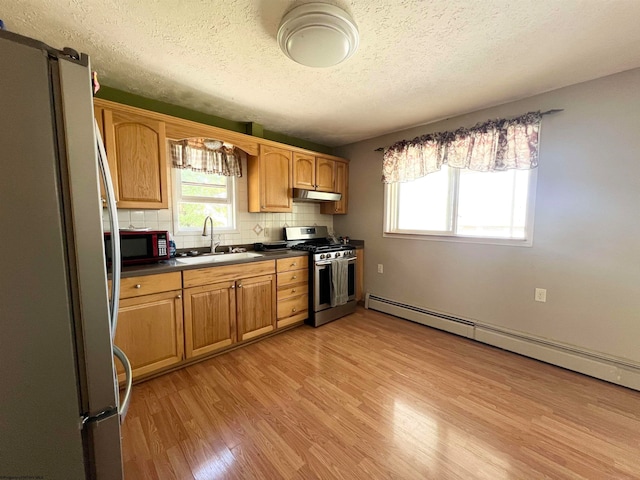 kitchen with stainless steel range with gas stovetop, white fridge, light hardwood / wood-style flooring, a baseboard radiator, and sink