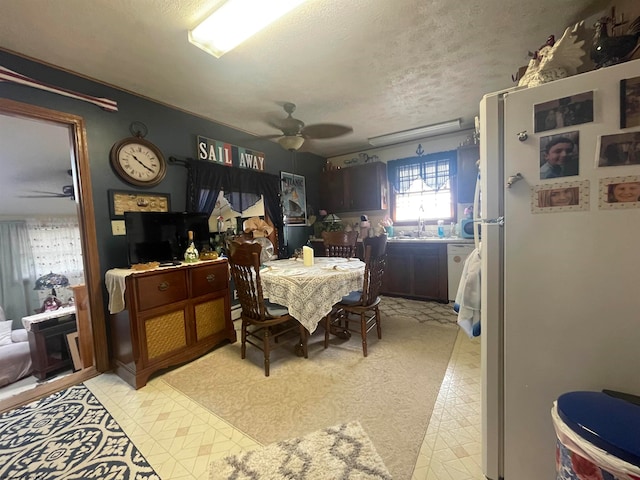 tiled dining area featuring a textured ceiling, sink, and ceiling fan