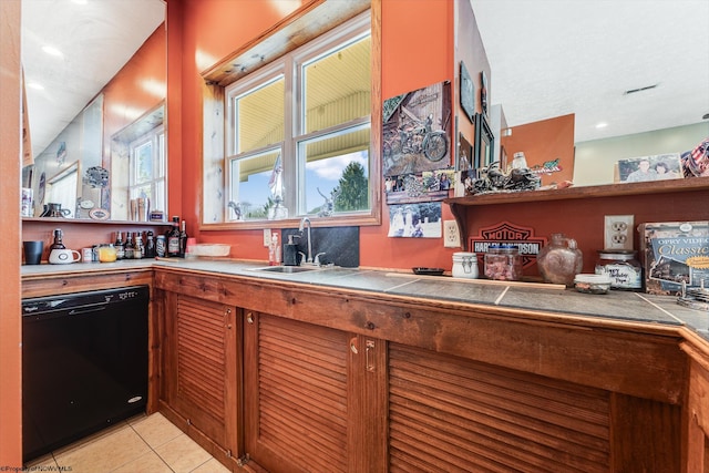 kitchen featuring dishwasher, sink, light tile patterned floors, and tile counters