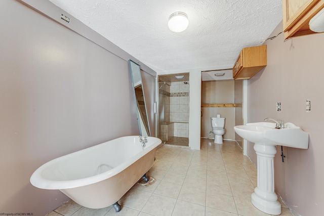 bathroom featuring a textured ceiling, toilet, tile patterned flooring, and shower with separate bathtub