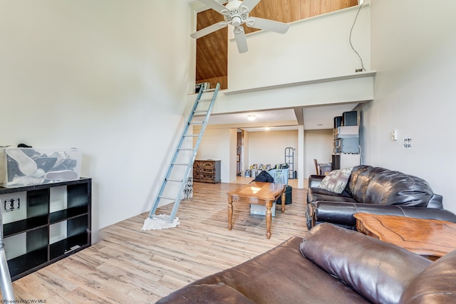 living room featuring ceiling fan, light wood-type flooring, and a high ceiling