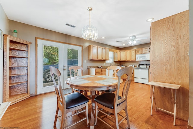 dining area featuring light wood-type flooring, ceiling fan with notable chandelier, and french doors