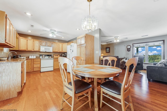 dining area featuring ceiling fan with notable chandelier, sink, and light hardwood / wood-style flooring