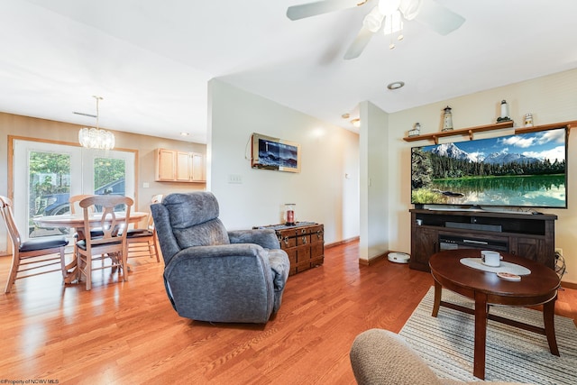 living room featuring ceiling fan with notable chandelier and hardwood / wood-style floors