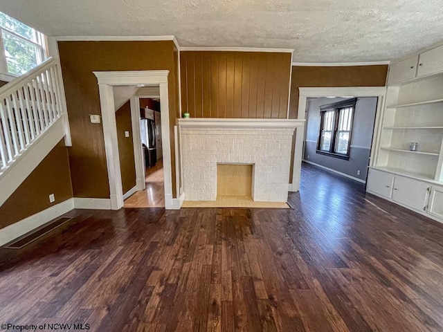 unfurnished living room with a textured ceiling, a healthy amount of sunlight, ornamental molding, and dark hardwood / wood-style flooring