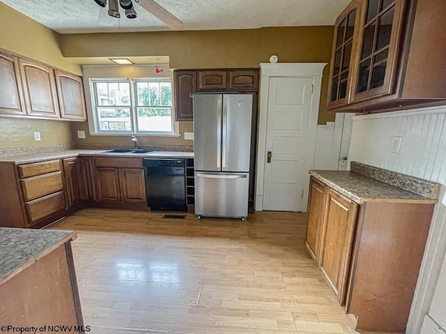 kitchen with stainless steel refrigerator, black dishwasher, ceiling fan, light hardwood / wood-style flooring, and sink