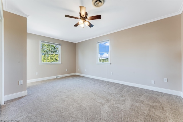 empty room with carpet, a ceiling fan, baseboards, visible vents, and crown molding