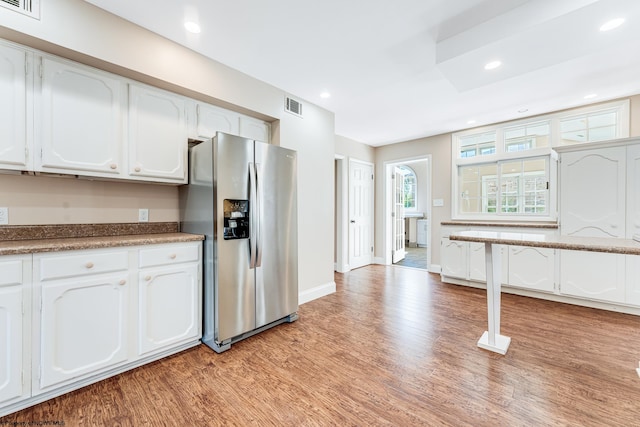 kitchen with white cabinets, light wood-type flooring, and stainless steel fridge