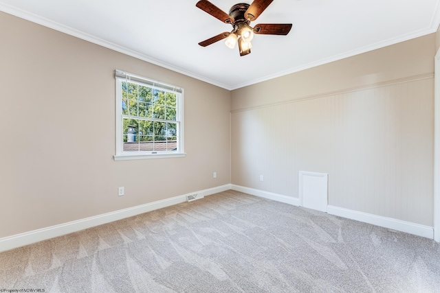 carpeted empty room featuring crown molding, baseboards, visible vents, and ceiling fan
