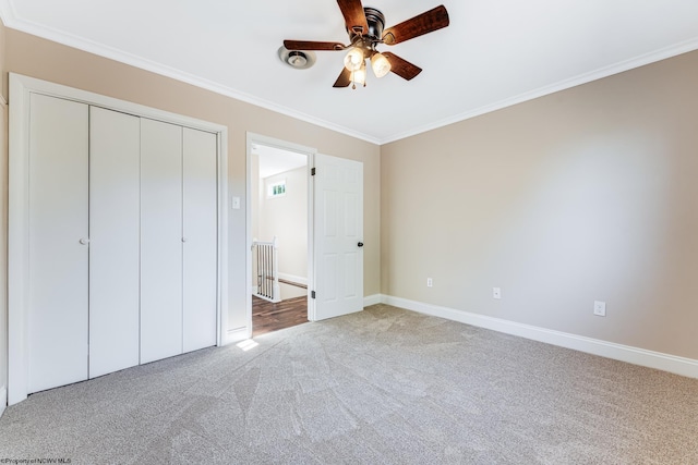 unfurnished bedroom featuring baseboards, ceiling fan, a closet, crown molding, and light colored carpet