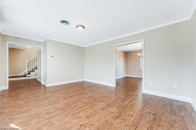 spare room featuring visible vents, wood finished floors, baseboards, a chandelier, and stairs