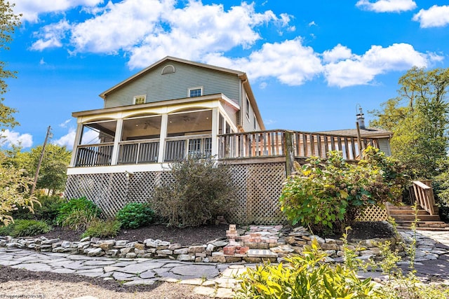 rear view of property featuring stairs, a deck, and a sunroom