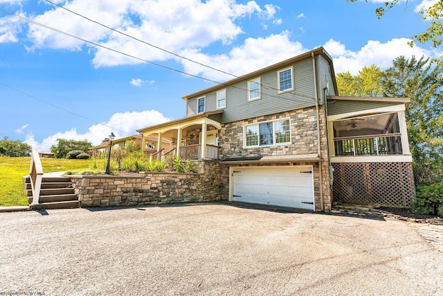 view of front of house featuring stairs, aphalt driveway, stone siding, and an attached garage