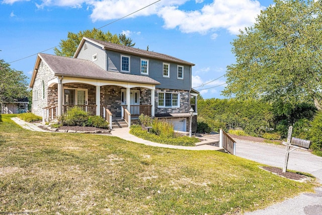 view of front of house with stone siding, an attached garage, a porch, and a front yard