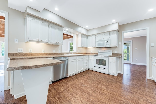 kitchen featuring wood finished floors, recessed lighting, white appliances, white cabinets, and baseboards