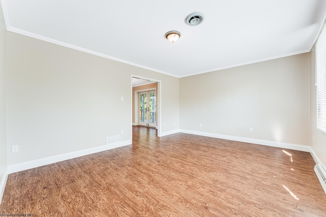 empty room with visible vents, ornamental molding, baseboards, and wood finished floors