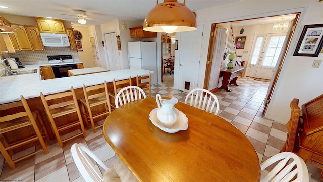 dining room featuring light tile patterned floors, ceiling fan with notable chandelier, and sink