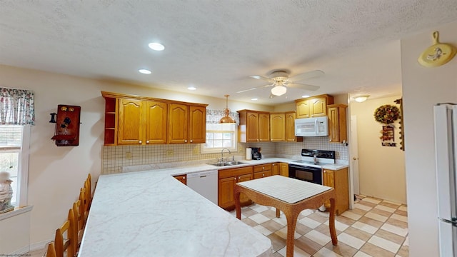 kitchen with tasteful backsplash, sink, hanging light fixtures, white appliances, and ceiling fan