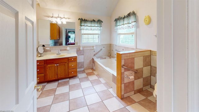 bathroom featuring tile walls, a bathing tub, vanity, lofted ceiling, and tile patterned floors