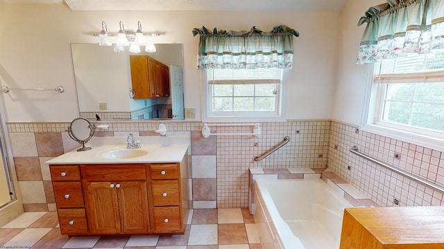 bathroom featuring tile patterned flooring, a wealth of natural light, a tub to relax in, and vanity