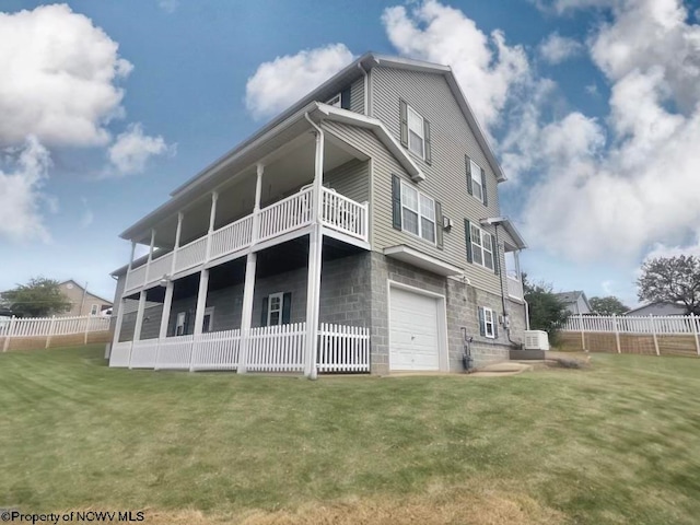 back of property with a balcony, a lawn, and a garage