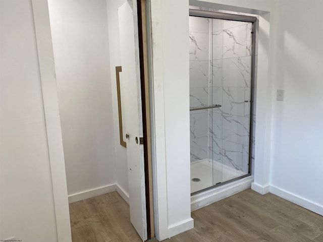 bathroom with a shower with door and hardwood / wood-style flooring