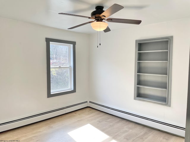 spare room featuring ceiling fan, a baseboard heating unit, and hardwood / wood-style floors