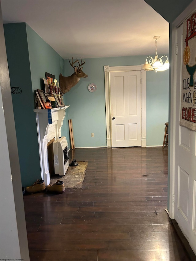 unfurnished living room featuring dark wood-type flooring, heating unit, and a chandelier