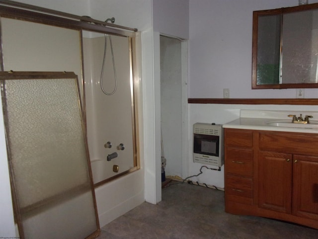 bathroom with bath / shower combo with glass door, heating unit, and vanity