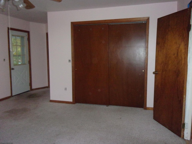 unfurnished bedroom featuring ceiling fan, a closet, and light carpet