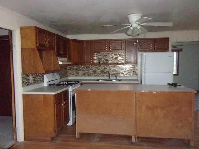 kitchen with white appliances, wood-type flooring, ceiling fan, ornamental molding, and sink