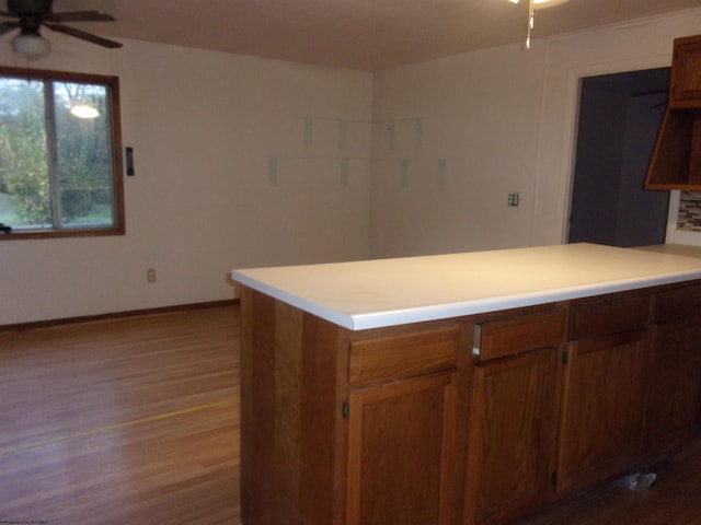 kitchen with light wood-type flooring, ceiling fan, and kitchen peninsula