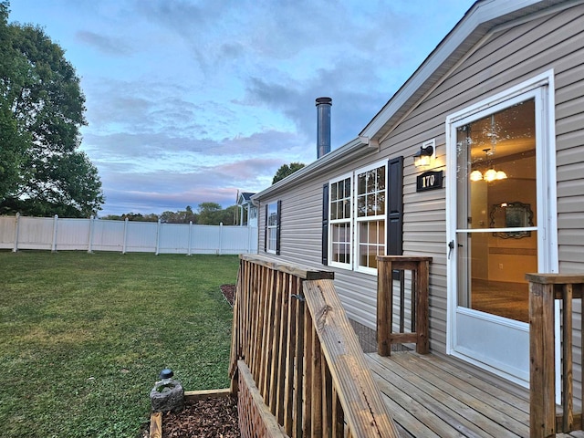 deck at dusk featuring a lawn