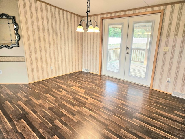 unfurnished dining area featuring french doors, a notable chandelier, dark hardwood / wood-style floors, and crown molding